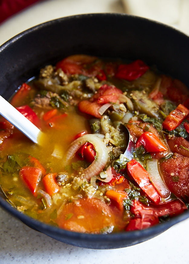 Beef vegetable soup in a pot with a ladle.