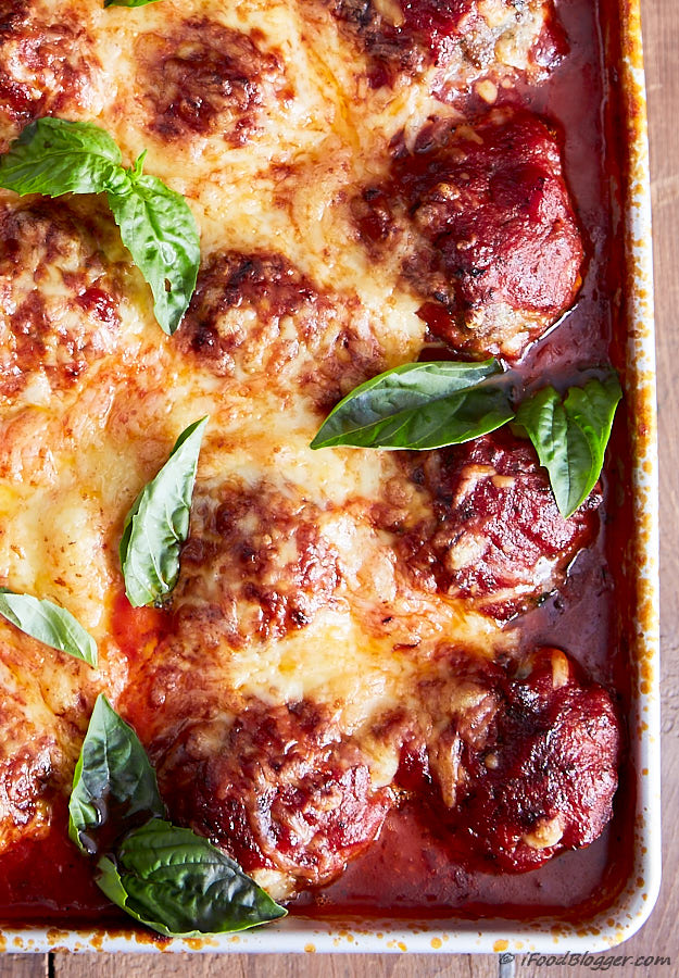 Italian meatballs in a baking dish with tomato sauce and melted cheese.