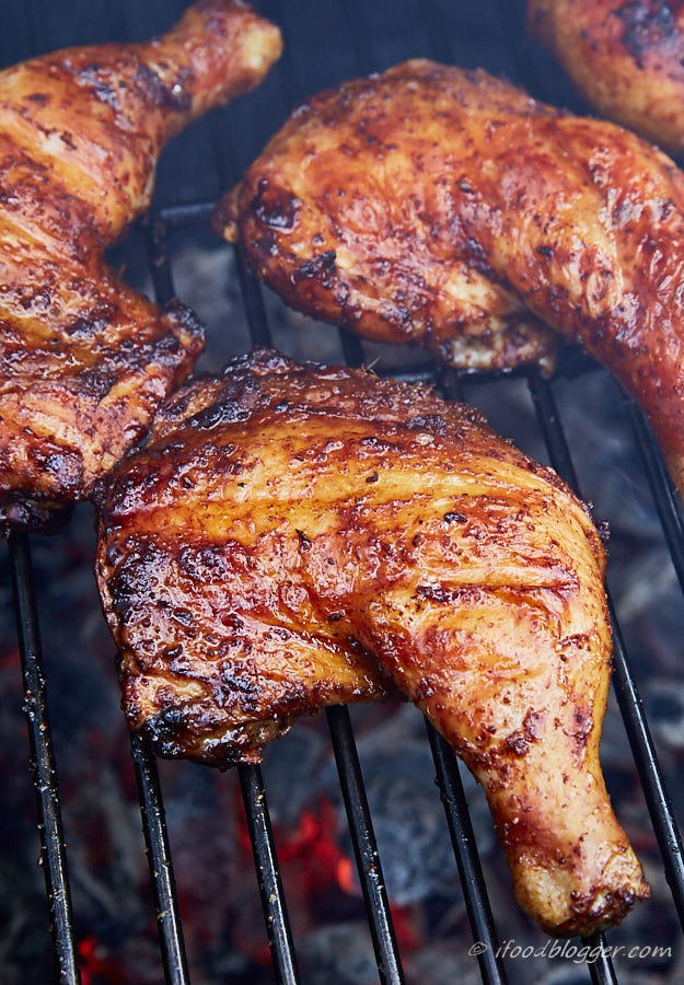 Chicken legs grilling on a charcoal grill.