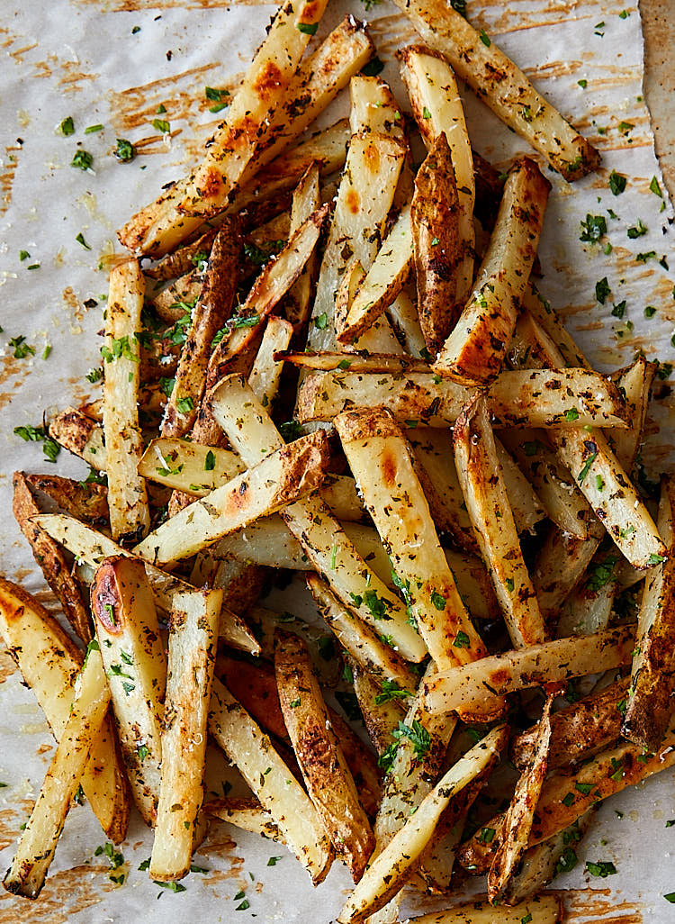 A top down view of a pile of Parmesan truffle fries, garnished with chopped parsley.