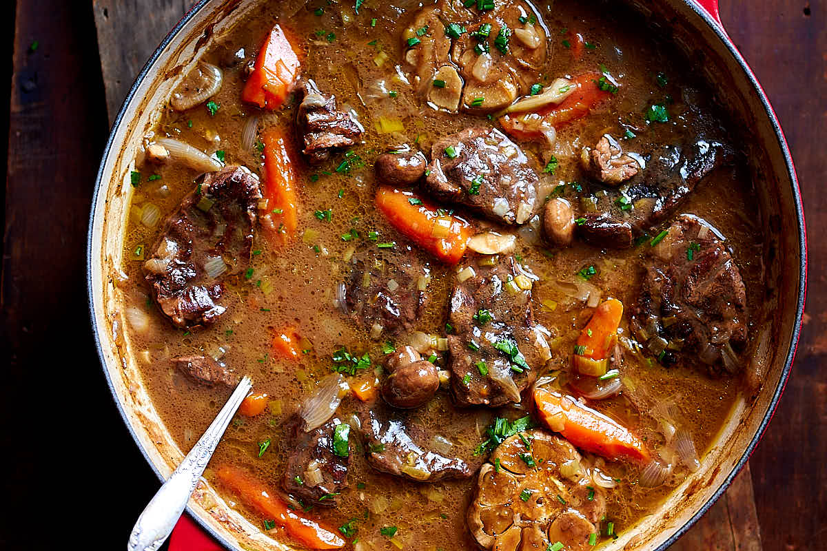 Braised beef cooked in a cast iron braising pan with mushrooms, leeks, carrots, onions, shallots and garlic. The sauce is thick and velvety smooth, like gravy. No thickening is needed after braising. Simply remove from the oven and serve with a side dish of choice. | ifoodblogger.com