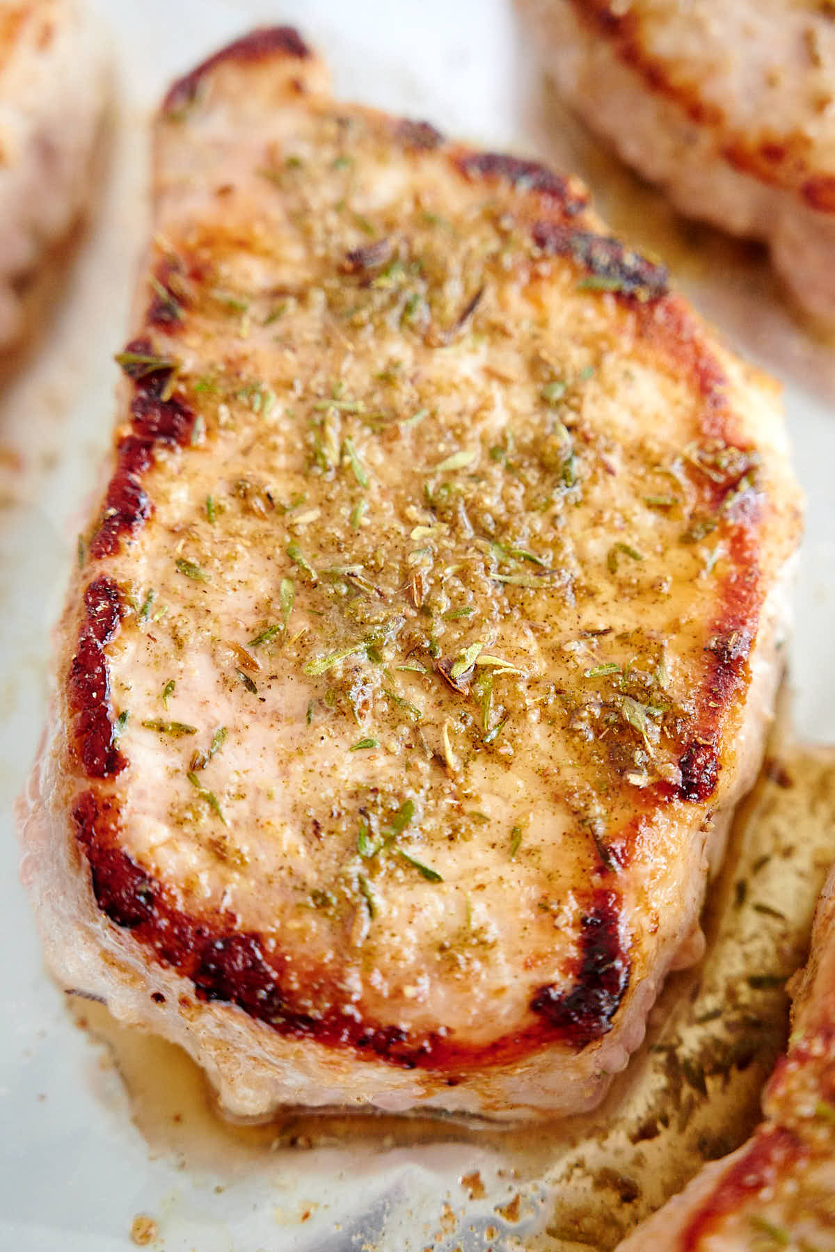 A closeup of a baked pork chop covered in spices.