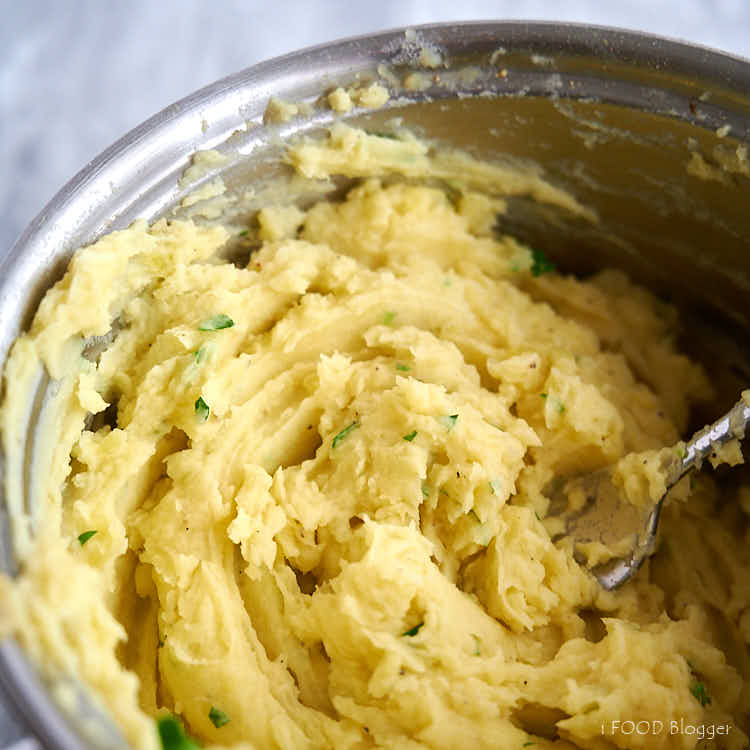 Whipping mashed potatoes with cream and herbs.