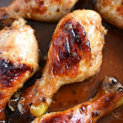 Baked chicken legs in a pan with pan sauce, square image.