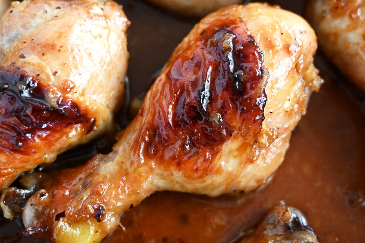 Baked chicken drumsticks, in a pan with sauce, golden brown color. Horizontal image.