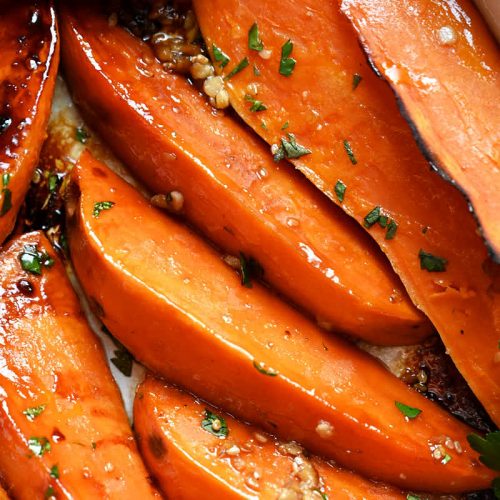 Roasted sweet potato wedges in a white baking dish.
