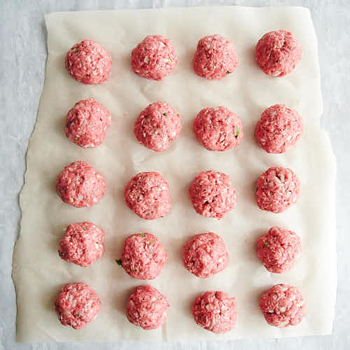 Shaped meatballs on a piece of parchment paper.